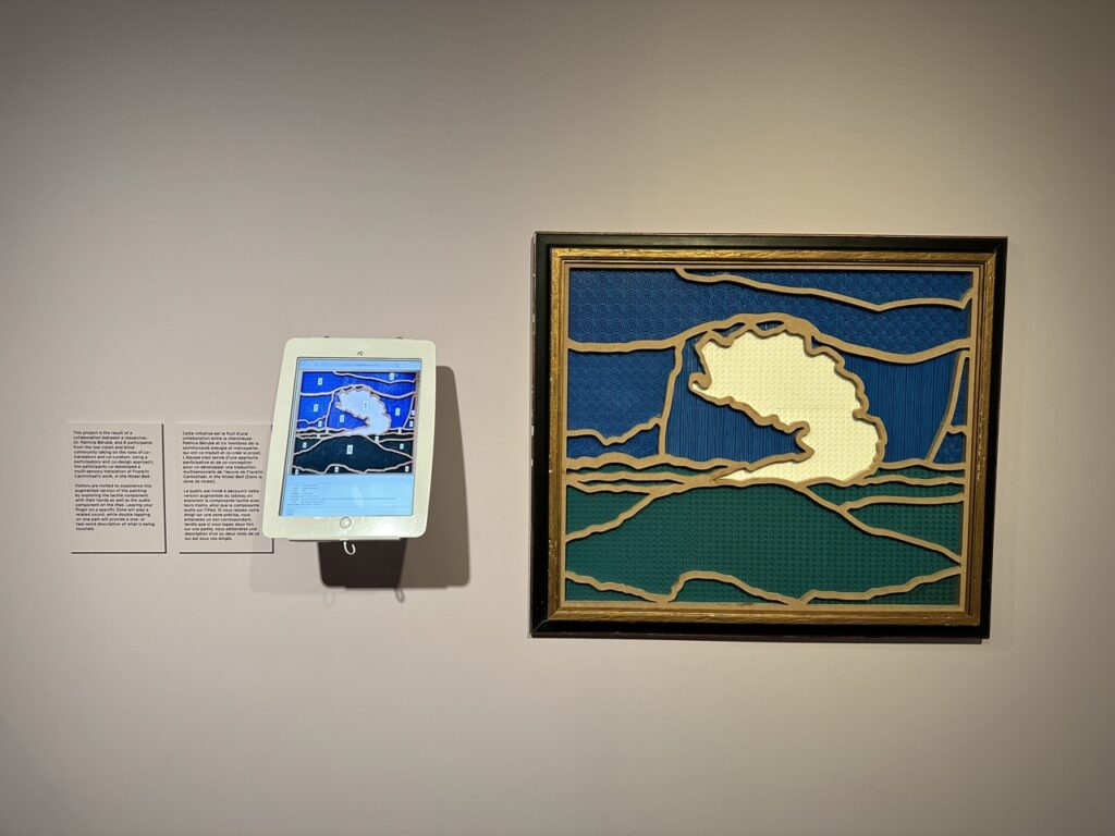 Wide view of the installation has the label in English and French to our left. The iPad, mounted off the wall at an angle is located directly to the label's right, and the tactile painting is to its right.